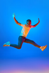 Obraz premium Neon light portrait of victorious delighted jumping man raising hands in star shape, shouting for joy, celebrating win success, thrilled emotions.