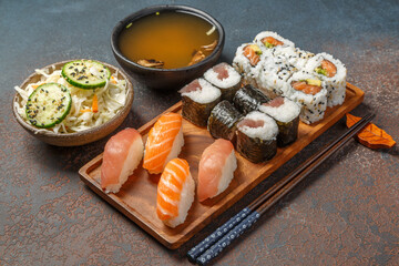Menu de sushi, maki et California rolls sur une planche en bois servie avec une soupe miso et salade de choux. Restaurant japonais. - obrazy, fototapety, plakaty