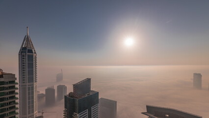 Rare early morning winter fog above the Dubai Marina skyline and skyscrapers lighted by sun aerial...