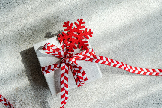 Overhead view of a gift box tied with a ribbon and snowflake ornament