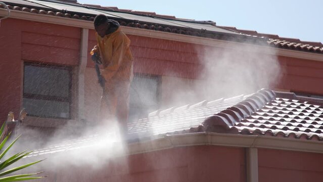 South Africa black man using a power wash to clean the gutters and wash the roof of a residential house