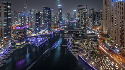 Aerial view to Dubai marina skyscrapers around canal with floating boats night timelapse