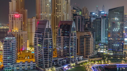 Dubai Marina skyscrapers and JBR district with luxury buildings and resorts aerial timelapse during all night with lights turning off