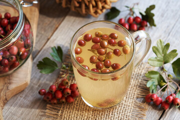 A glass cup of herbal tea with fresh hawthorn berries