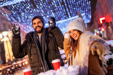 Couple having snowball fight while spending Christmas Eve in the city streets