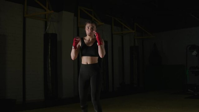 Young woman fighter trains his kicks in the boxing gym, front view, 4k slow motion.