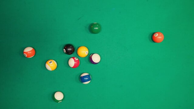 A young man plays Russian billiards, an American woman in a billiards club and bar. Dark colors in the billiard club. A man pockets snooker balls.