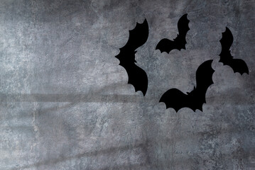 Halloween greeting card concept; Black bats flying on the dark gray background with sunlight and shadow