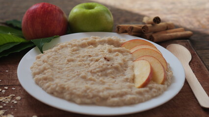Plate of oatmeal porridge with red apple slices and cinnamon. Close up.