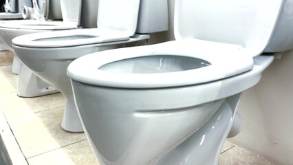 toilet in plumbing store. bathroom equipment a many toilets stand on the floor in the store. repair replacement of the toilet in the bathroom choice in the plumbing lifestyle store