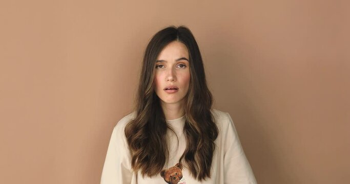 Brunette indignant woman showing blah blah blah gesture with hands isolated on studio beige background. Empty promises, blah concept. Lier, not interested. Annoyed girl making bla bla bla hand gesture