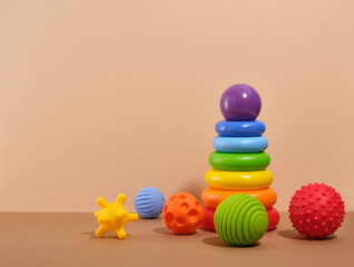 Colorful tactile or sensory balls and pyramid with colored rings on a beige background. Copy space...