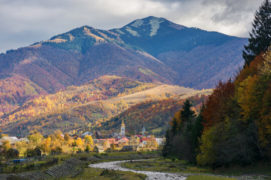 rural landscape with river in the outskirts of the village. countryside scenery among mountains in autumn. kolochava, ukraine