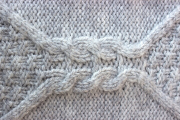 Texture of gray knitted sweater with braids