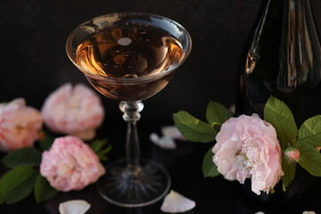 Glass of pink champagne with rose flowers on the black background