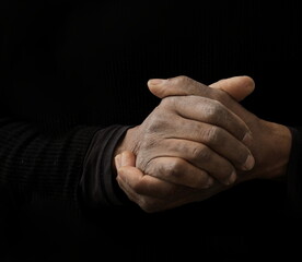 man praying to god with hands together on dark background with people stock image stock photo	