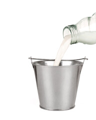 Fresh milk is poured from a bottle in a metal bucket, isolated on white.