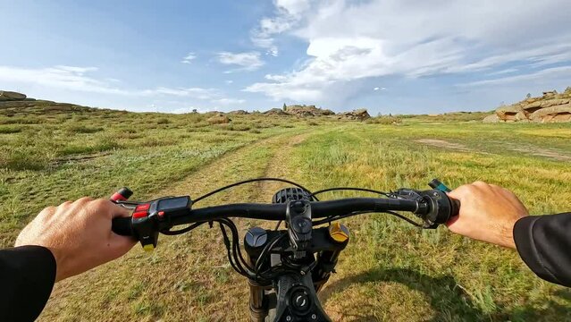 POV Electric Bike Riding on a Country Road in Mountainous Terrain with Stone Monoliths at Partly-Cloudy Day. 60 fps, H.264, 8bit, chroma subsamlping 4:4:4