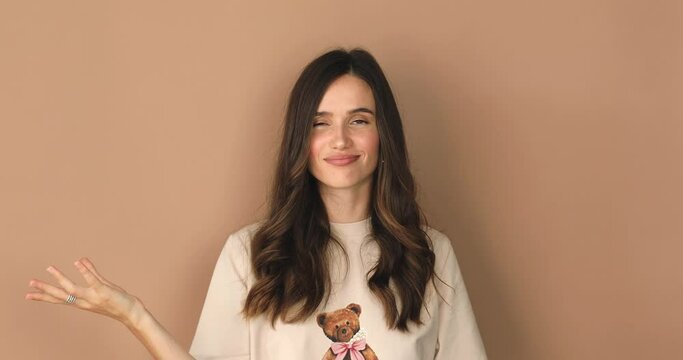 Brunette woman on a beige background with a gesture showing that she liked the treat. Belisimo. Girl pout lips show belissimo perfect sign, gesture of a good taste.