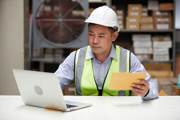 factory worker reading and looking at envelope in the office or warehouse storage