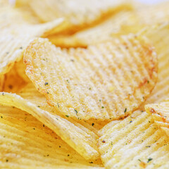 Appetizing crispy potato chips with texture and seasoning background in selective focus, fast food.Macro photography.