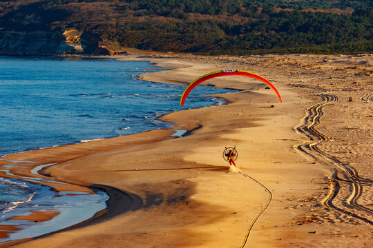 Aerial view of paramotor pilot foot dragging on natural sand beach at the Black Sea coast of Istanbul, Turkey.