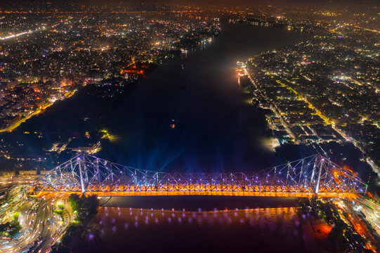 Aerial view of architectural landmark Howrah bridge or Rabindra Setu over the Hooghly River at night in Kolkata, West Bengal, India.