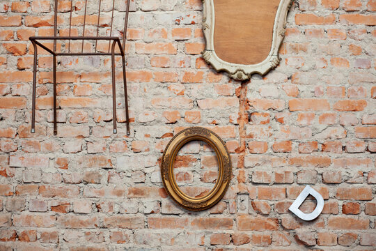 brick wall with hanging objects: chair, frames and a D