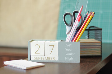 27 September. Image of september 27 wooden calendar on desktop. Autumn day. Back to school. Pencils and paints, stationery