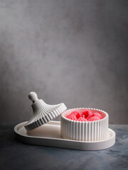 Scented candle with raspberry scent in a ceramic stand with a lid standing on a table and copy space at the top of the photo.