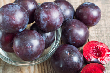 Ripe plums in bowl on a wooden table