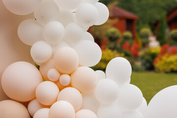 Various air balloons of different pastel colours and sizes. Details of creative gender neutral babyshower or birthday party decoration outdoors. Festive photo zone arch kit