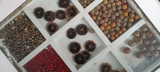 Various types of dried fruits and nuts in a wooden box on a white background