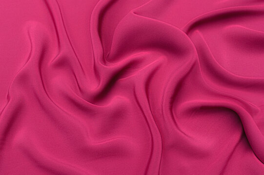 Close-up texture of natural red or pink fabric or cloth in same color. Fabric texture of natural cotton, silk or wool, or linen textile material. Red and pink canvas background.