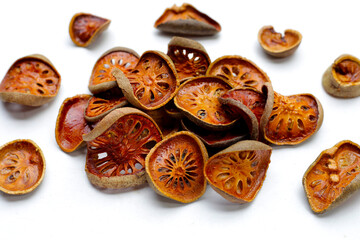 Dried bael fruit slices on white background.