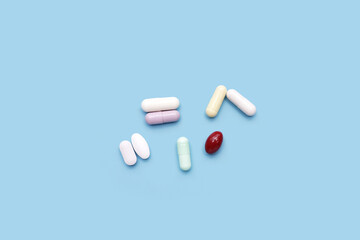 Colorful capsules and pills on blue background.