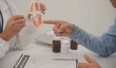 Dentists are discussing dental problems at report x-ray image on laptop screen to patients.