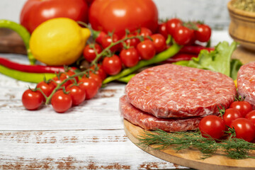 Raw hamburger patties on wood background. Raw veal hamburger patties with herbs and spices. Copy space. Free space for text