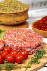 Raw hamburger patties on wood background. Raw veal hamburger patties with herbs and spices. Close up