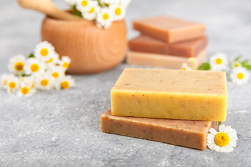 Natural homemade soap with chamomile flowers on a wooden table. Close-up of moisturizing soap with natural herbal oils. Spa and beauty concept. Place for text. Copy space.Fletley
