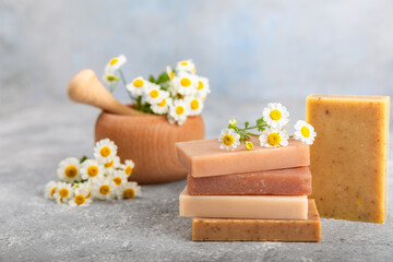 Fototapeta na wymiar Natural homemade soap with chamomile flowers on a wooden table. Close-up of moisturizing soap with natural herbal oils. Spa and beauty concept. Place for text. Copy space.Fletley