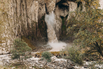 A high, stormy waterfall flowing down the massive rocks of Djily-su. A journey through the mountain beauty of the Caucasus.