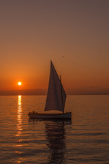 Fototapeta premium View of a sailboat sailing on the lake at sunset.