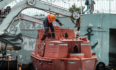 davit launched liferaft onshore, old rusty ship lifeboat, resque training stcw on vessel, seafarer education, orange safety boat