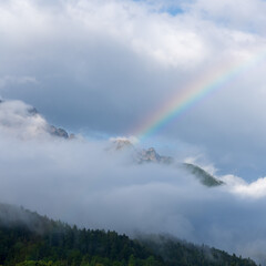 A rainbow over a mountain peak that is shrouded in clouds in Triglav National Park in Slovenia