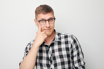 Portrait of young male pointing finger at spectacles on face isolated on white studio background....