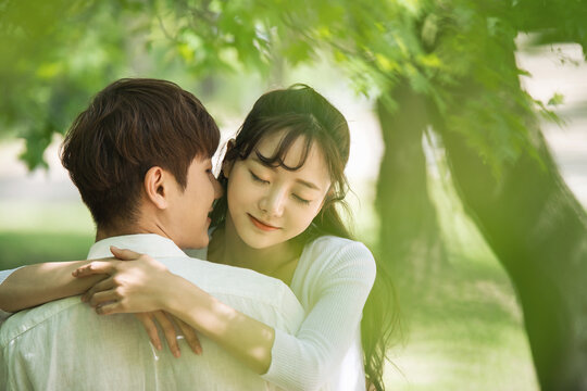 A lovely young couple are having fun in a forested park.