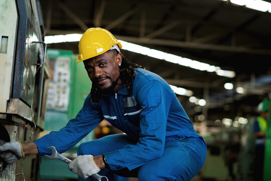 Black male African American worker is working in an industrial factory. manufacturing industry concept Machinery in the factory Metal grinder in factory - Powered by Adobe