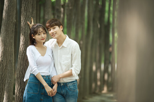 A lovely young couple are having fun in a forested park.