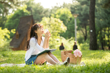 The young woman is having a good time drinking drinks and reading books in a forested park.